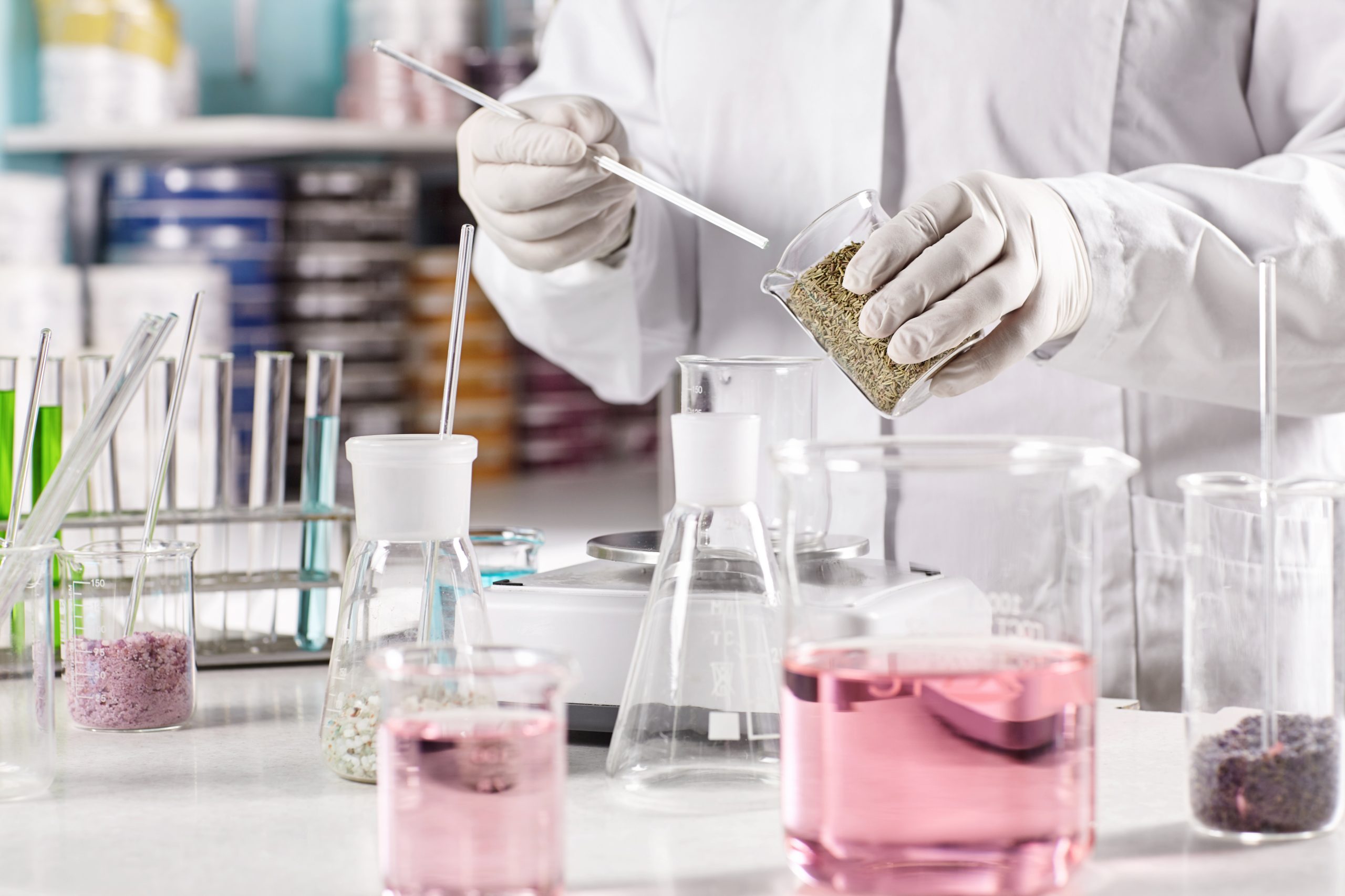worker-surrounded-with-glass-beakers-filled-with-colorful-liquid.jpg